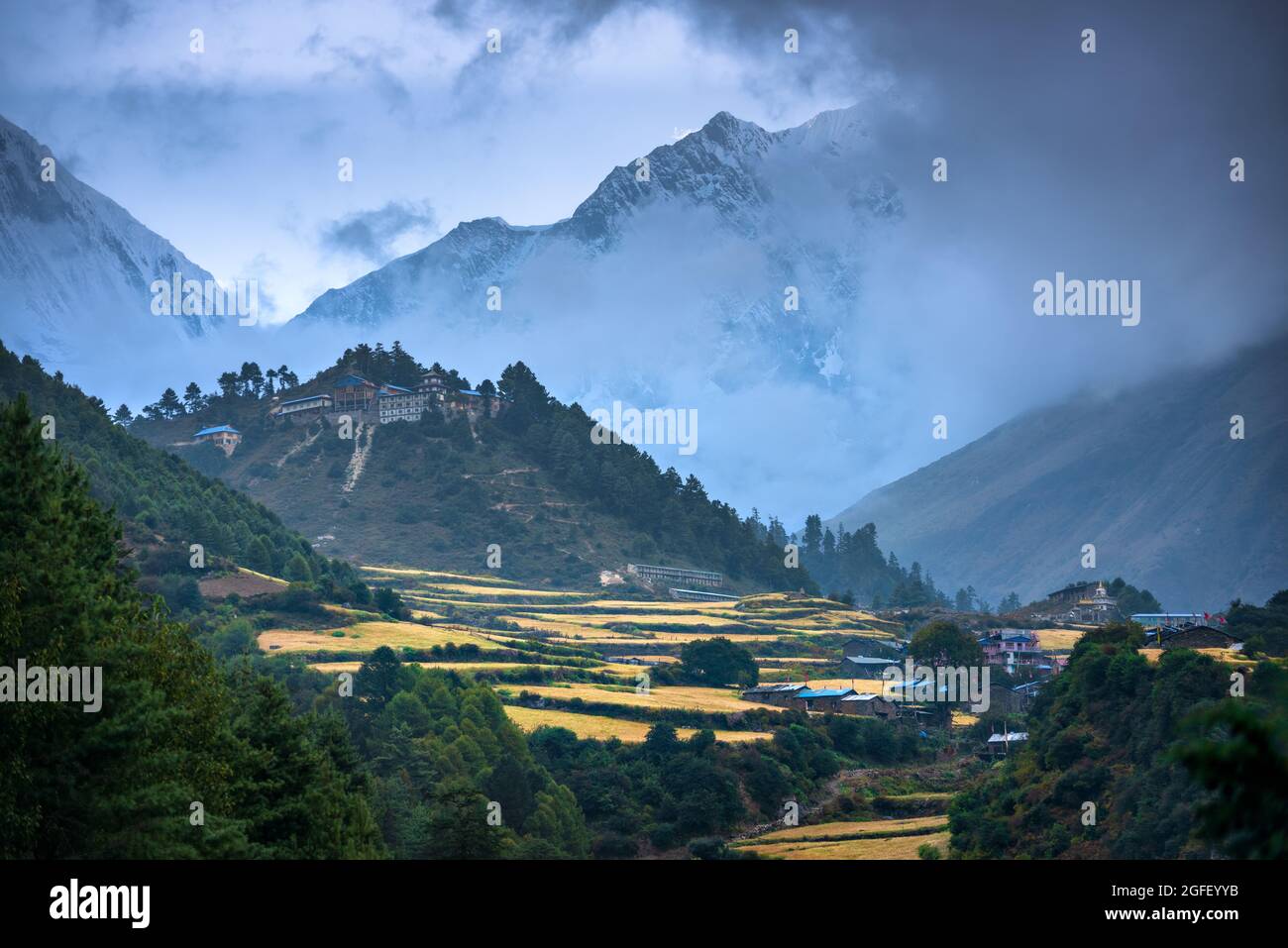 Pequeño pueblo en el pico de la montaña en niebla al atardecer en Nepal Foto de stock