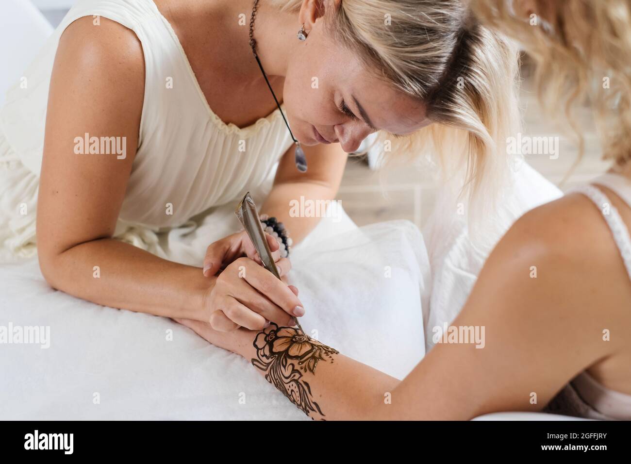 Artista que aplica tatuaje de henna en las manos de la mujer. Mehndi es arte decorativo tradicional indio, mano con mehendi floral. Dibujo de belleza para bodas y. Foto de stock