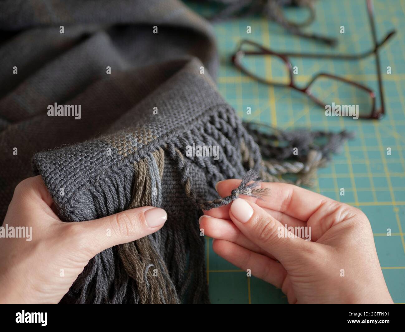 Artisan está en acción. La mujer está creando un flecos en una bufanda de  lana o silenciador. Manos de artesano con producto tejido Fotografía de  stock - Alamy