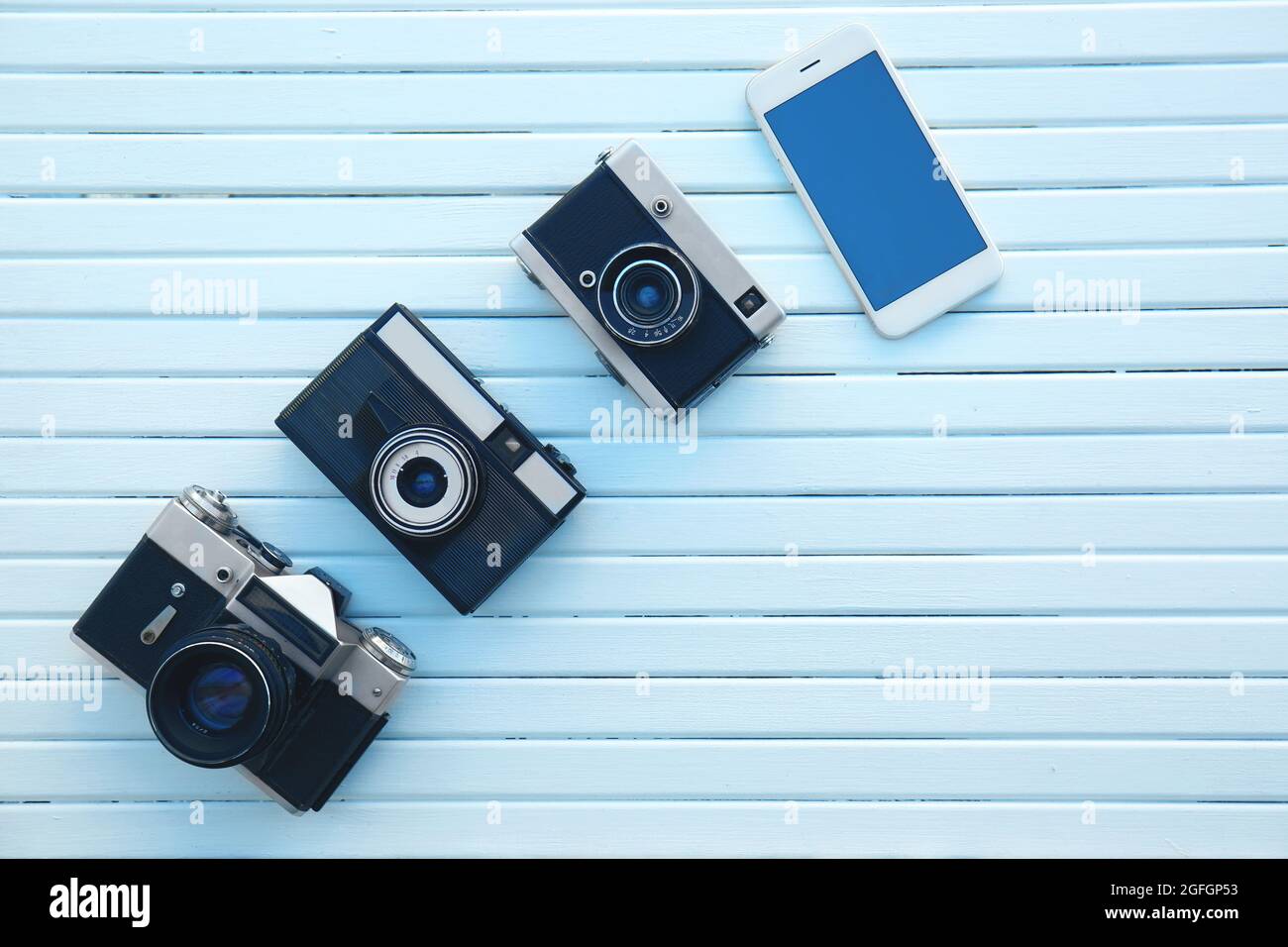 Concepto de evolución de la cámara. Cámaras antiguas y modernas sobre fondo  de madera blanca Fotografía de stock - Alamy