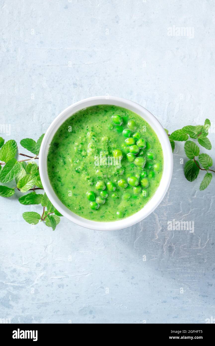 Sopa vegana con guisantes verdes y menta, rodada desde arriba con espacio de copia. Comida saludable de desintoxicación. Dieta vegetal oragónica Foto de stock