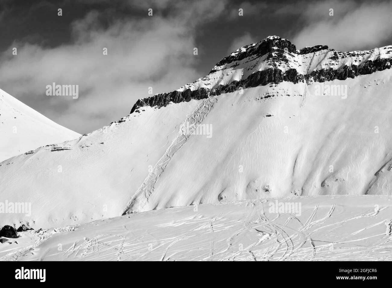 Pista fuera de pista con rastros de esquís, snowboards y avalanchas. Montañas del Cáucaso en el sol día de invierno, Georgia, región Gudauri. Tonos blanco y negro l Foto de stock