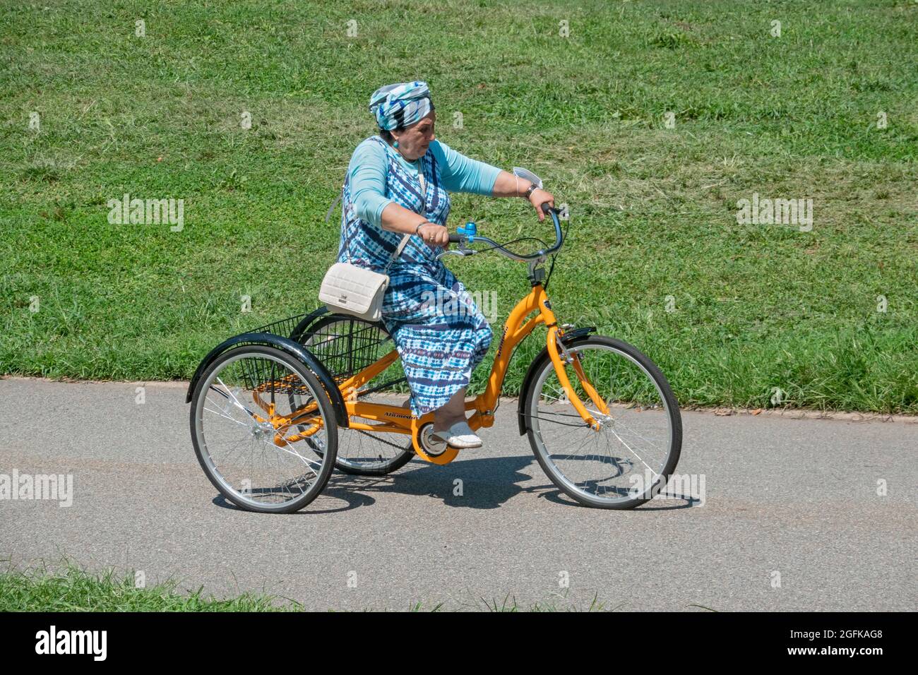 Una mujer mayor coordinada de color en un turbante monta un triciclo adulto  alameda en Kissena Park, Flushing, Queens, Nueva York Fotografía de stock -  Alamy