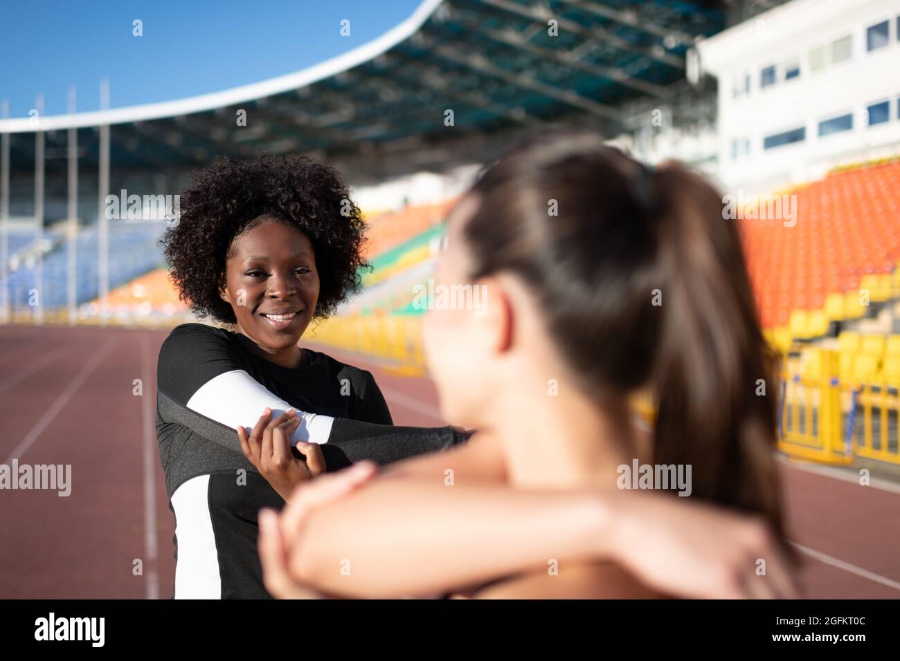 Mujer atleta negra sonriendo y hablando con su novia mientras se calienta Foto de stock