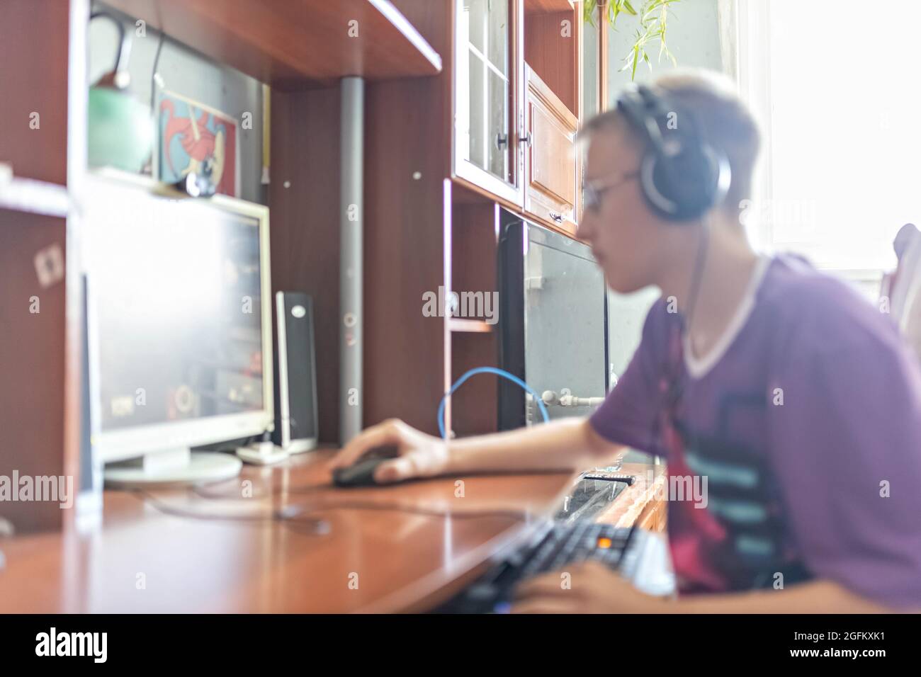 Un adolescente, un joven jugando a videojuegos en una computadora, usando tecnología, usando auriculares, usando un hombre joven, un adolescente usando tec Foto de stock