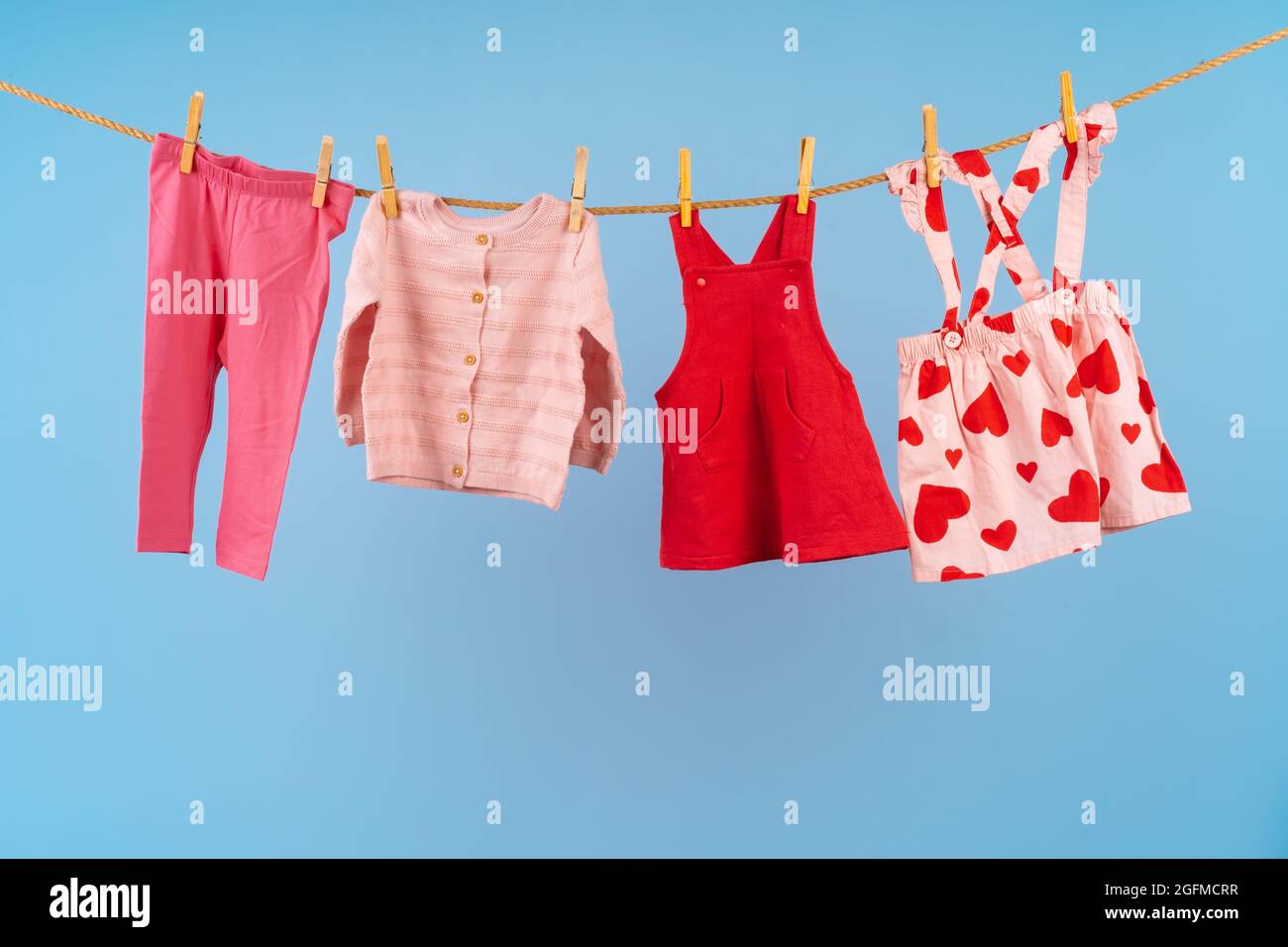 Ropa de niña fijada en una línea de ropa contra fondo azul Fotografía de  stock - Alamy