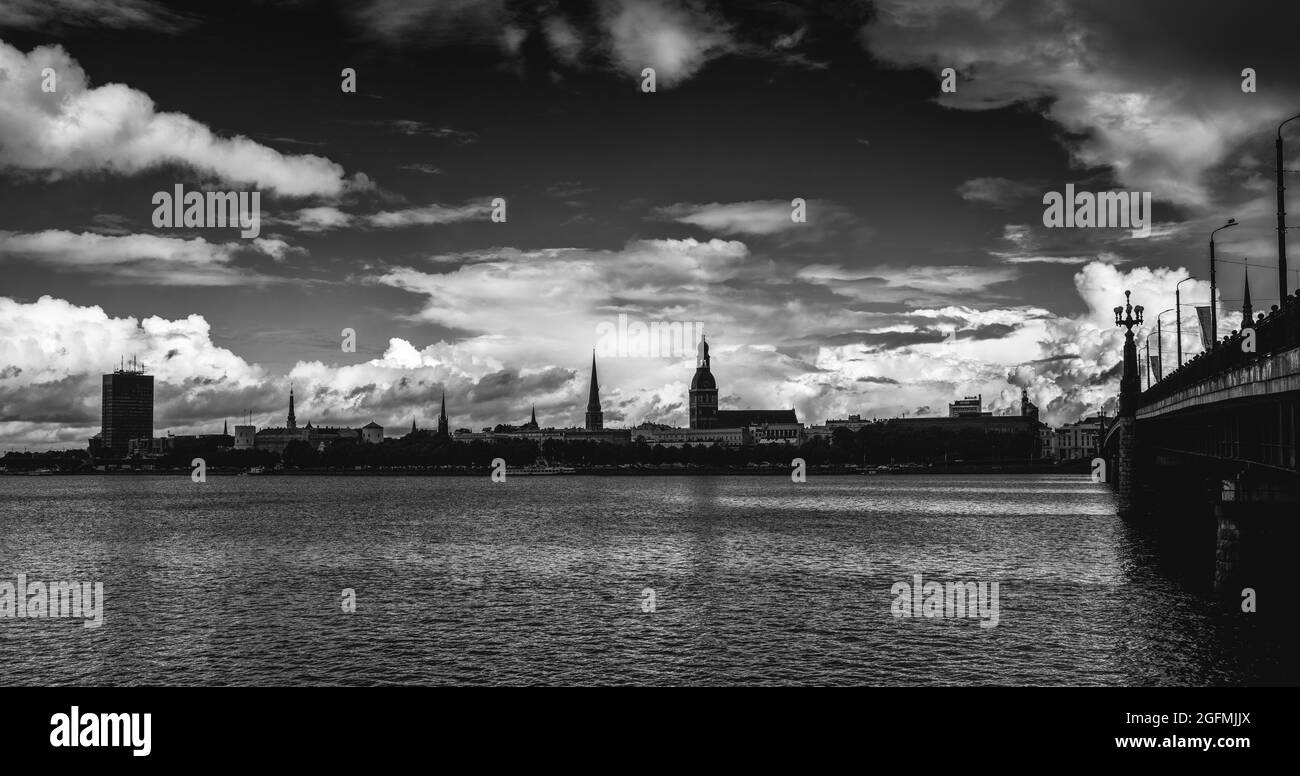 Riga, Letonia - 19 de agosto de 2021: El río Daugava y el puente Akmens inclinan el horizonte de Riga al fondo Foto de stock
