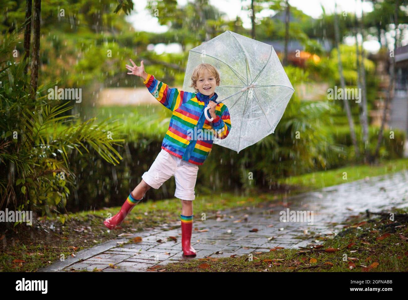 Niños jugando bajo la lluvia de otoño. Niño con paraguas. Niño