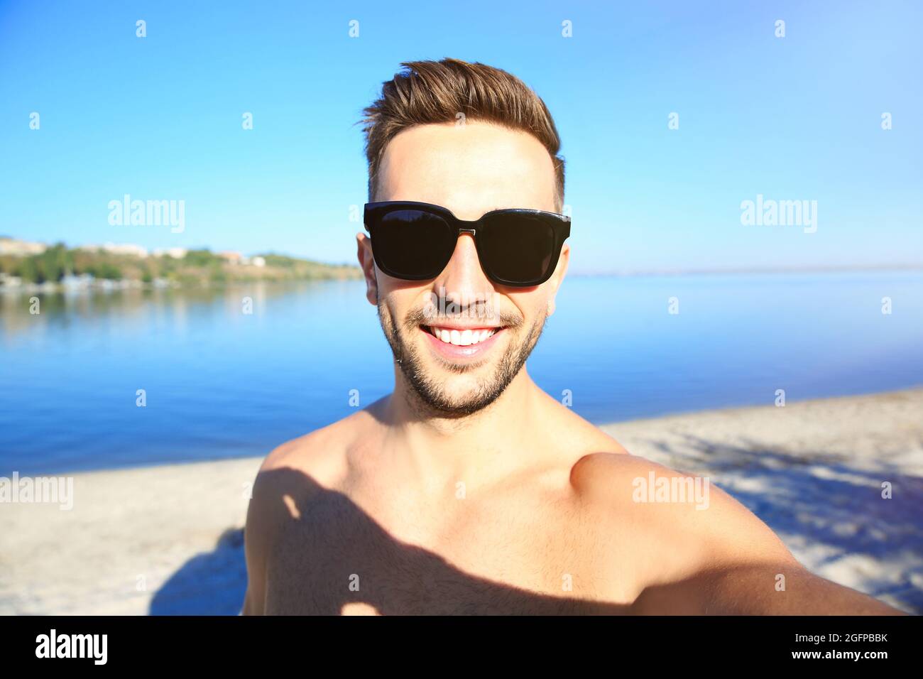 Hombre guapo en gafas de sol tomando selfie en la playa Fotografía de stock  - Alamy