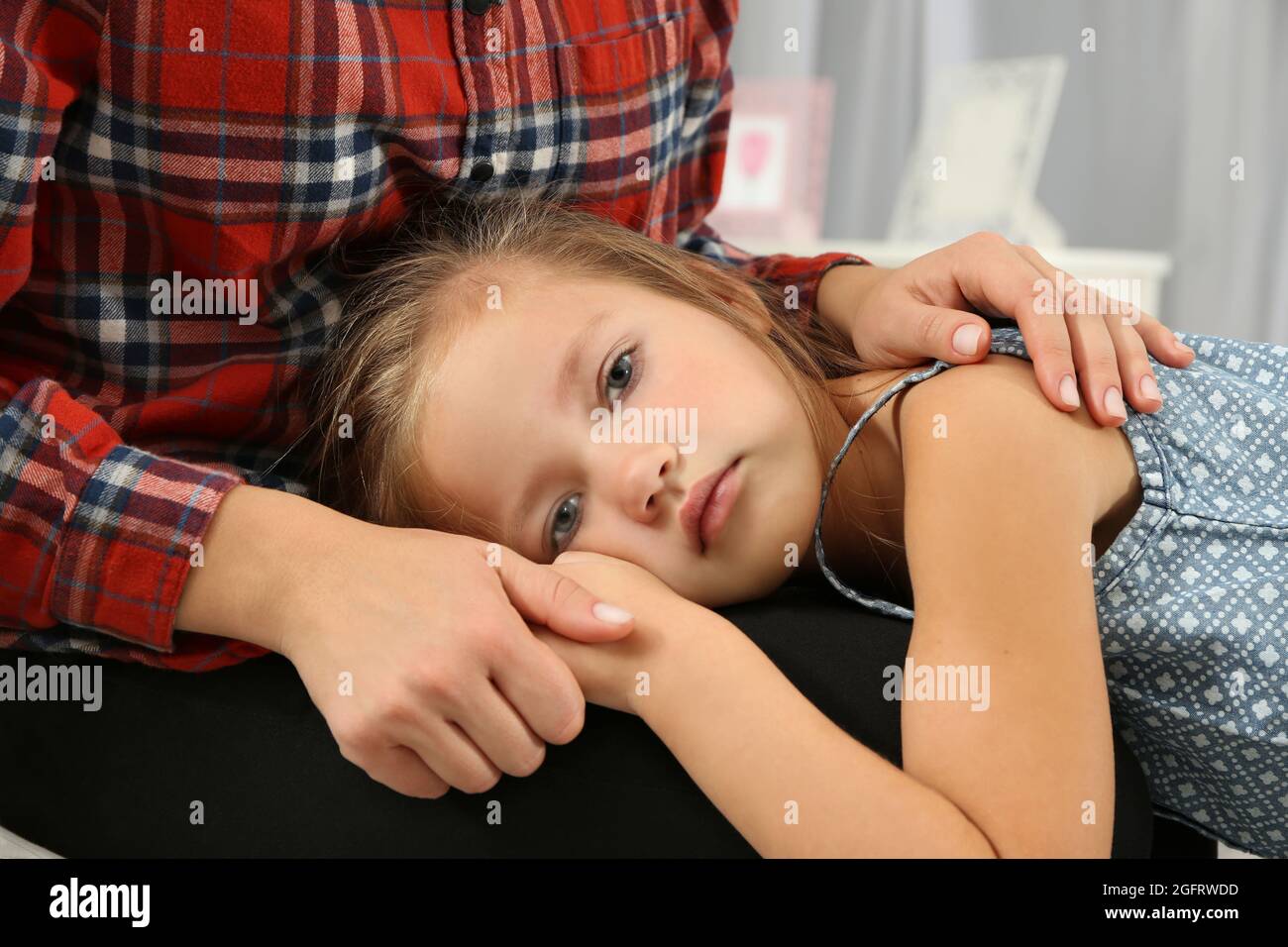 Cute Little Girl poniendo la cabeza sobre las rodillas de la madre, Vista cercana Foto de stock