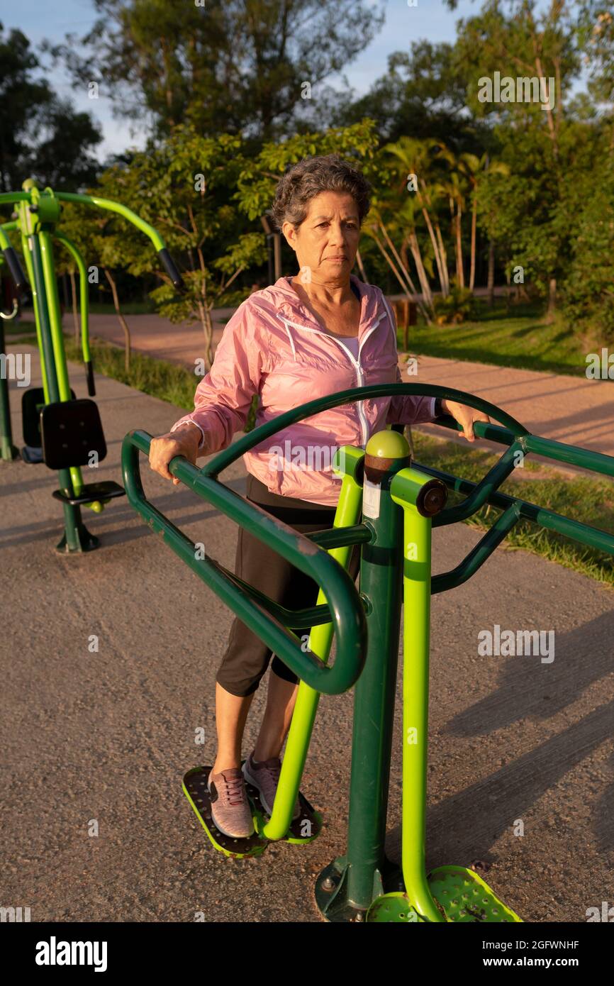 Mujer brasileña negra seria con piernas entrenamiento de ropa deportiva y cardio en equipo de gimnasio. Mañana afuera en parque y bosques. Superar, Fotografía de stock - Alamy