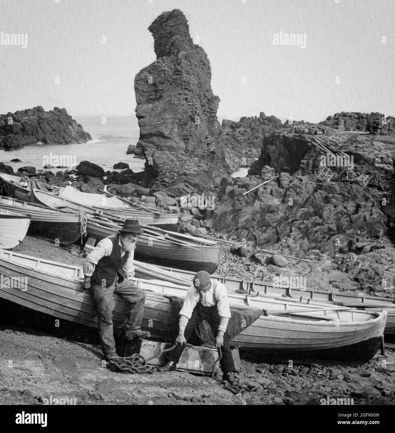 Una vista de principios del siglo 20th de los pescadores que se preparan para un día de pesca en la playa cerca de la Calzada del Gigante en el Condado de Antrim, Irlanda del Norte. Foto de stock