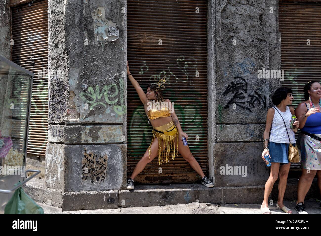 Brasil – 16 de febrero de 2020: Una mujer vestida de oro que se inclina contra la puerta oxidada actúa durante el Carnaval callejero celebrado en el centro de Río de Janeiro. Foto de stock