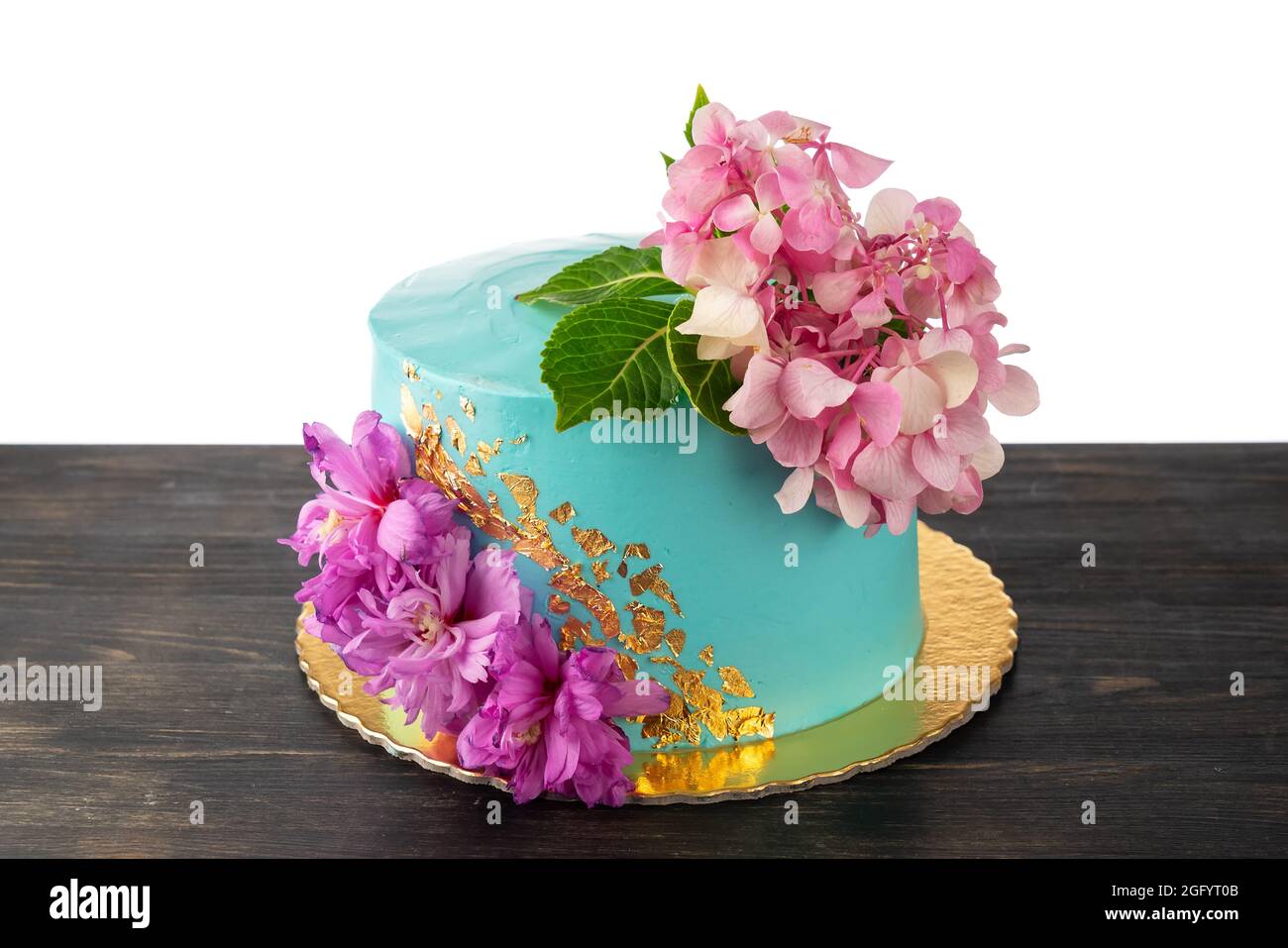 Un hermoso concepto pastel hecho de crema azul y flores. Sobre una mesa de  madera, sobre un fondo blanco Fotografía de stock - Alamy