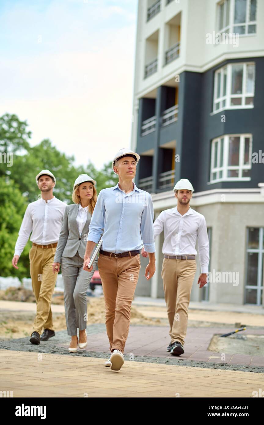 Grupo de cuatro personas que realizan la supervisión de un nuevo proyecto de construcción Foto de stock