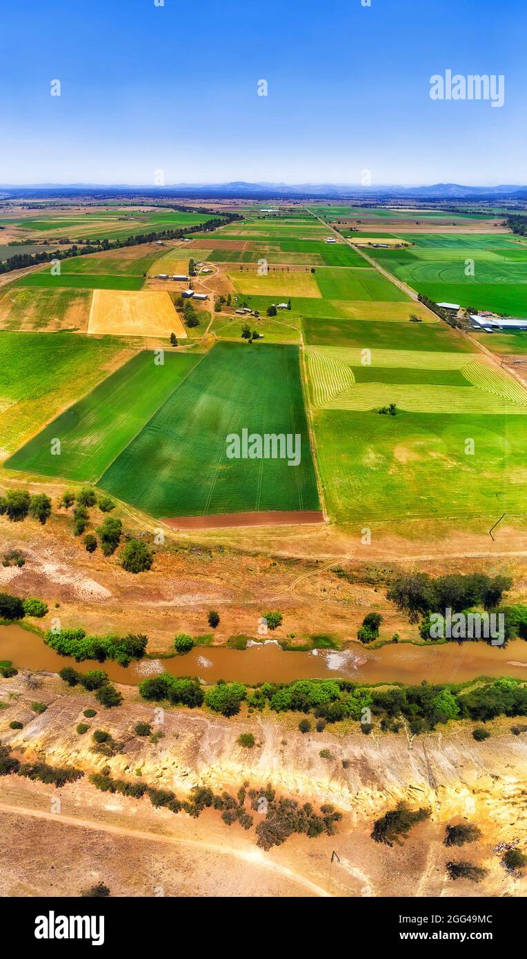 Árido Outback australiano en el valle de Hunter, a orillas del río Hunter, con verde granja agrícola cultivada - panorama vertical aéreo. Foto de stock