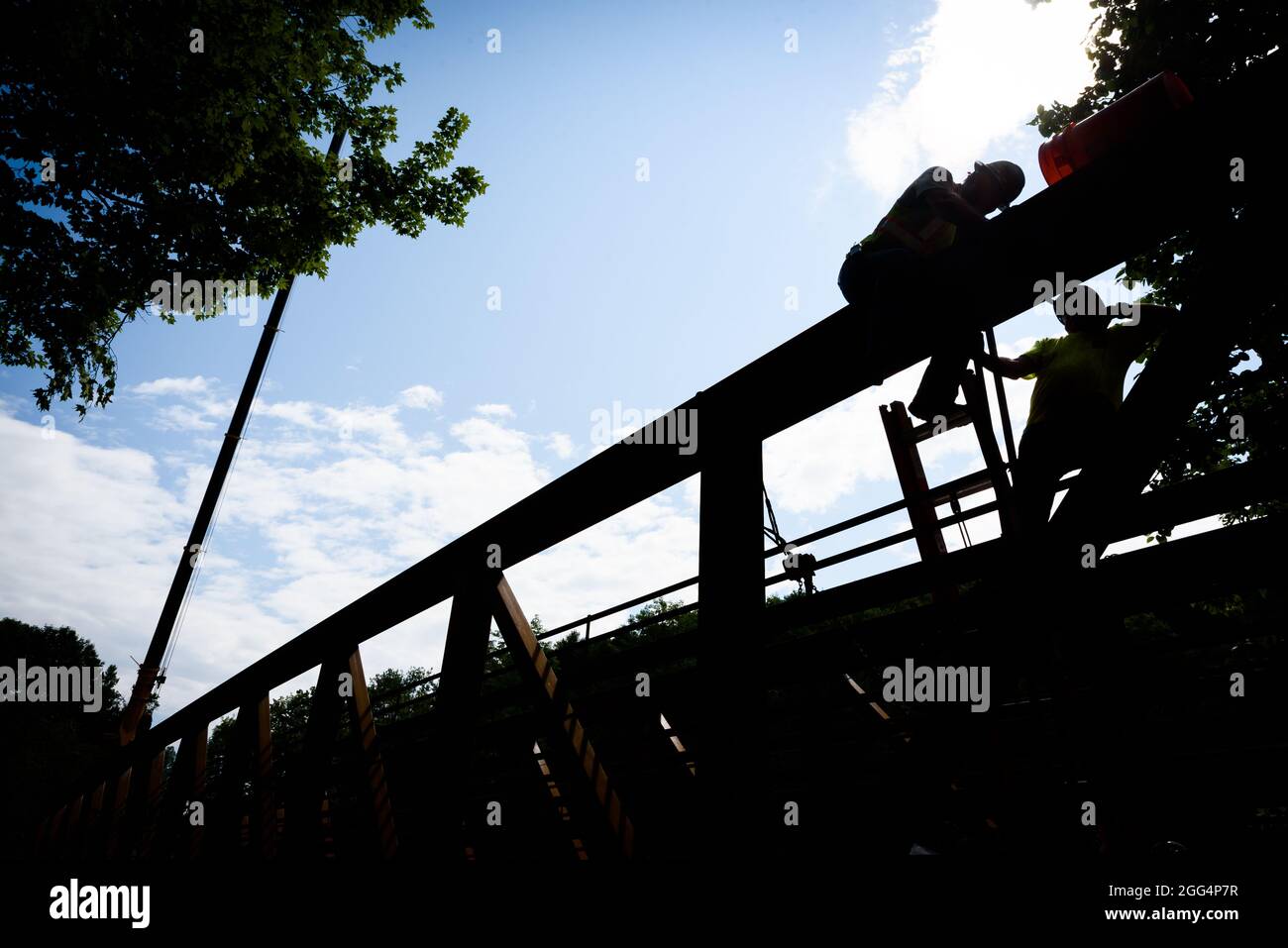 Los obreros se perfilan contra un cielo azul como un puente de acero se está construyendo en la Cross Vermont Trail, East Montpelier, VT, EE.UU Foto de stock