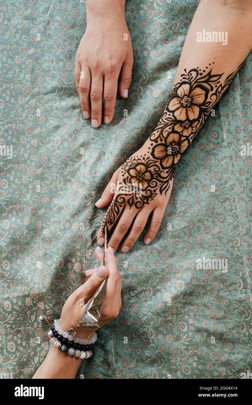 Artista que aplica tatuaje de henna en las manos de la mujer. Mehndi es arte decorativo tradicional indio, mano con mehendi floral. Dibujo de belleza para bodas y. Foto de stock