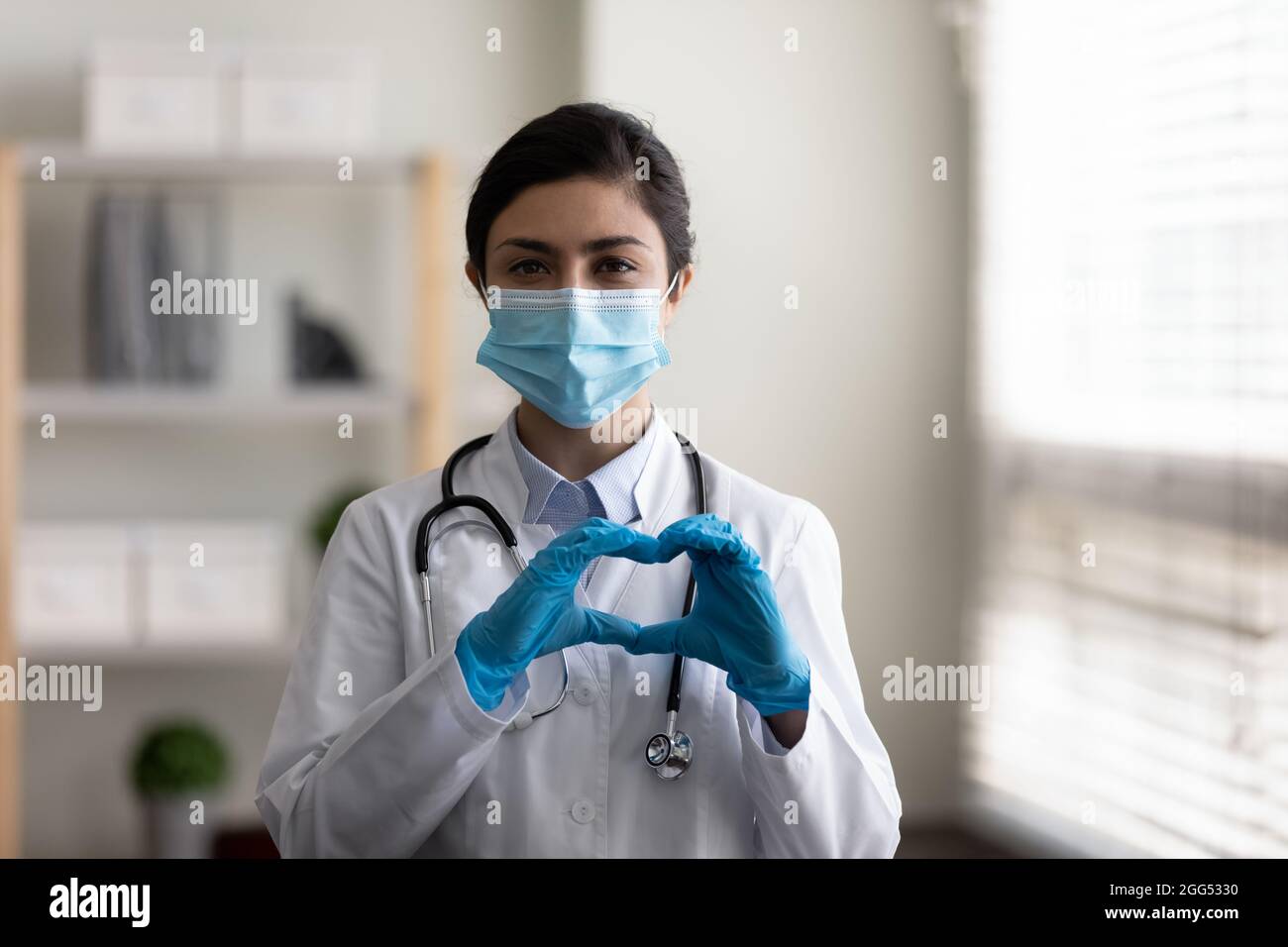 Feliz joven médico indio que muestra signos de corazón. Foto de stock