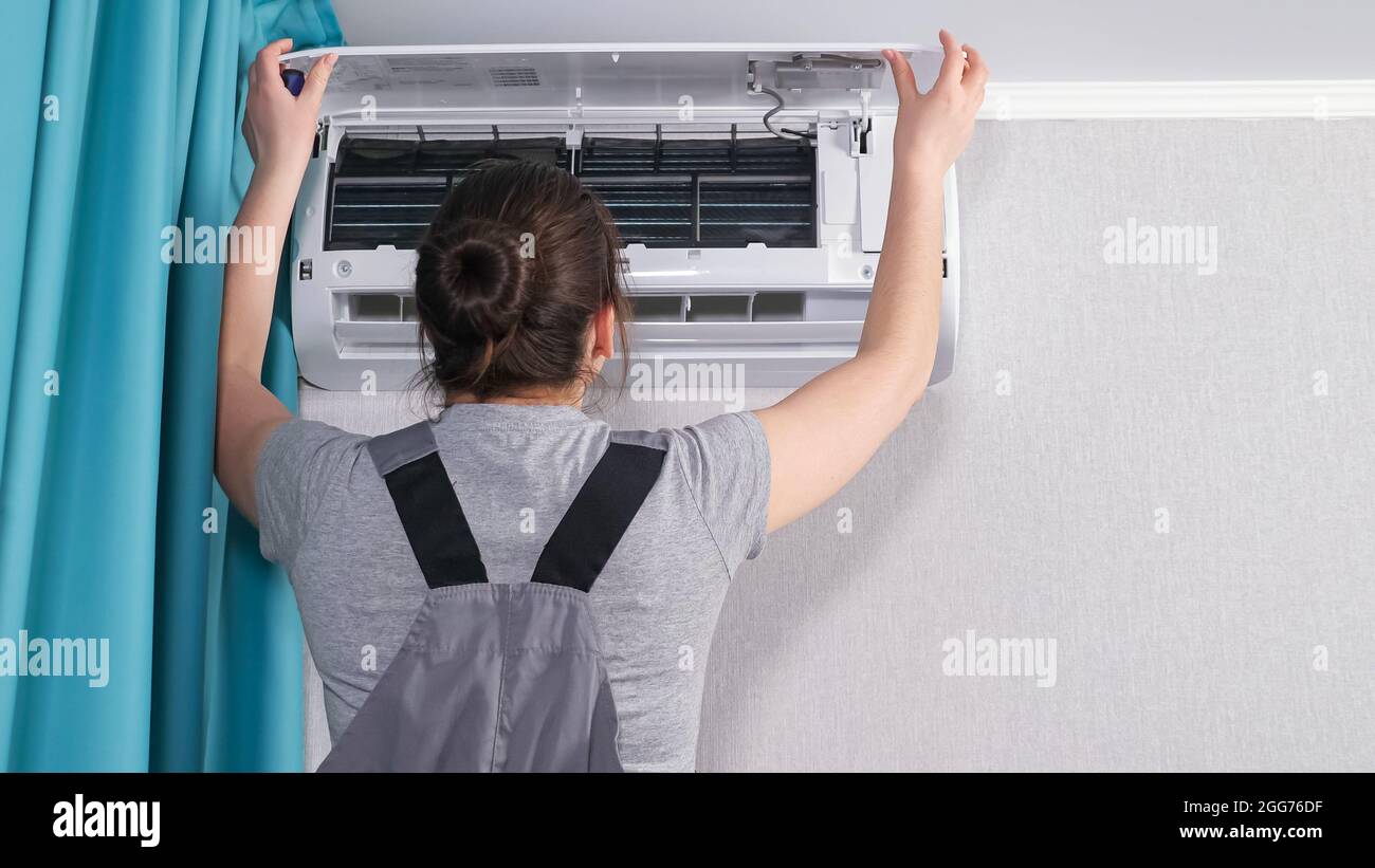 Una mujer en la ropa de trabajo abre la cubierta blanca de la unidad de aire  acondicionado Fotografía de stock - Alamy