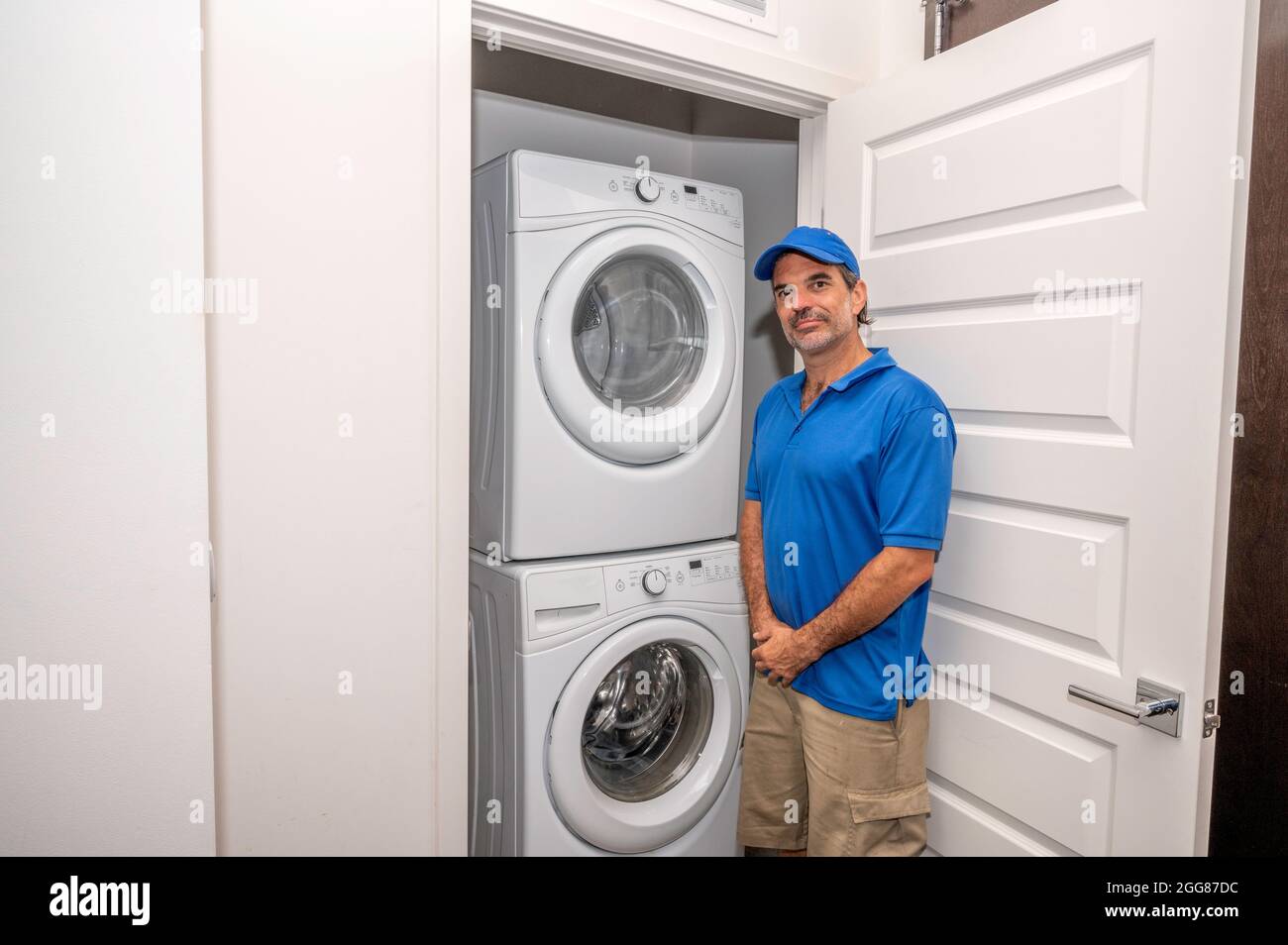 Técnico de electrodomésticos de pie junto a una lavadora y secadora  modernas en una pequeña sala de lavandería Fotografía de stock - Alamy