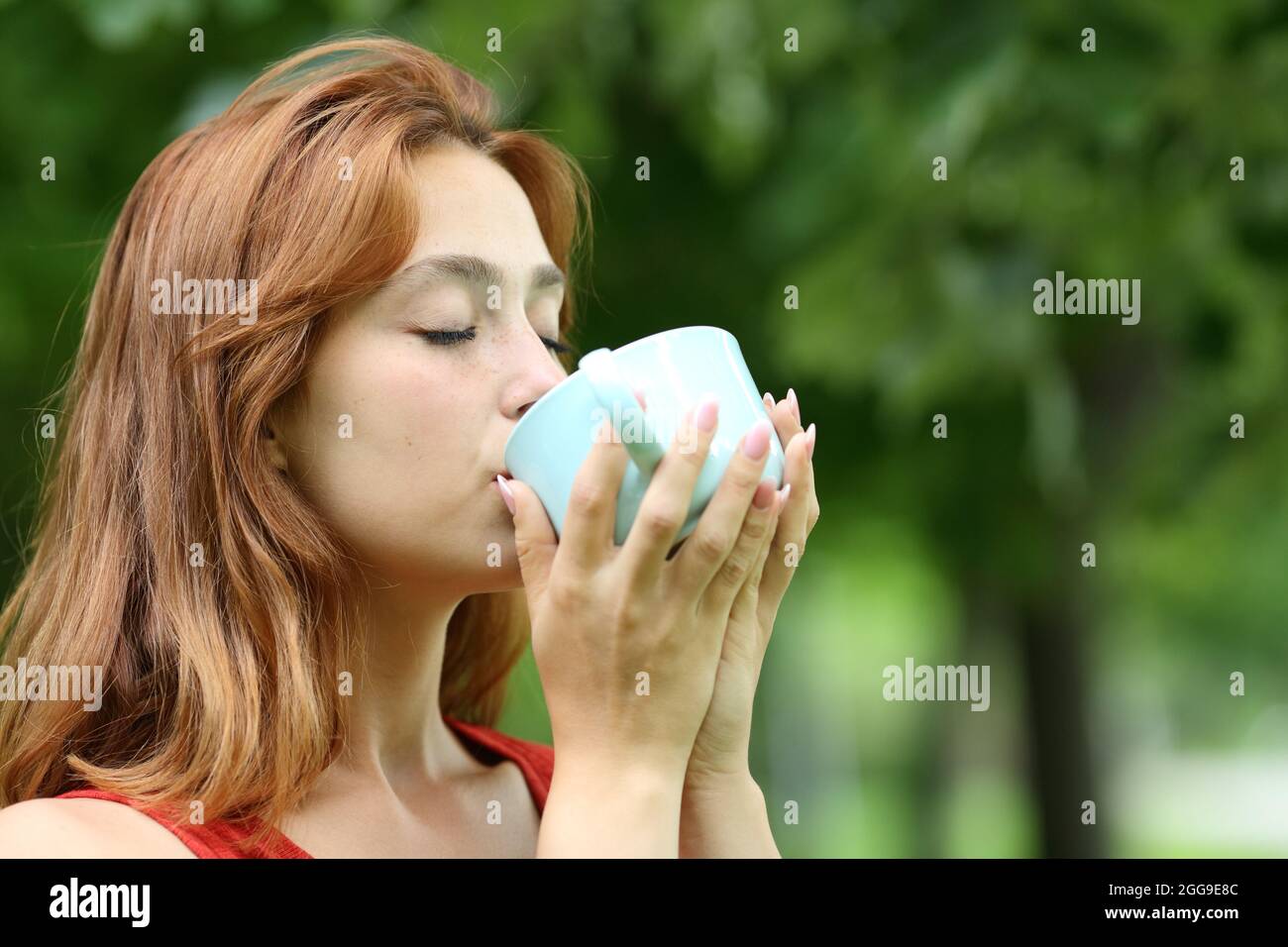 Mujer relajada bebiendo café de la taza en un parque Foto de stock