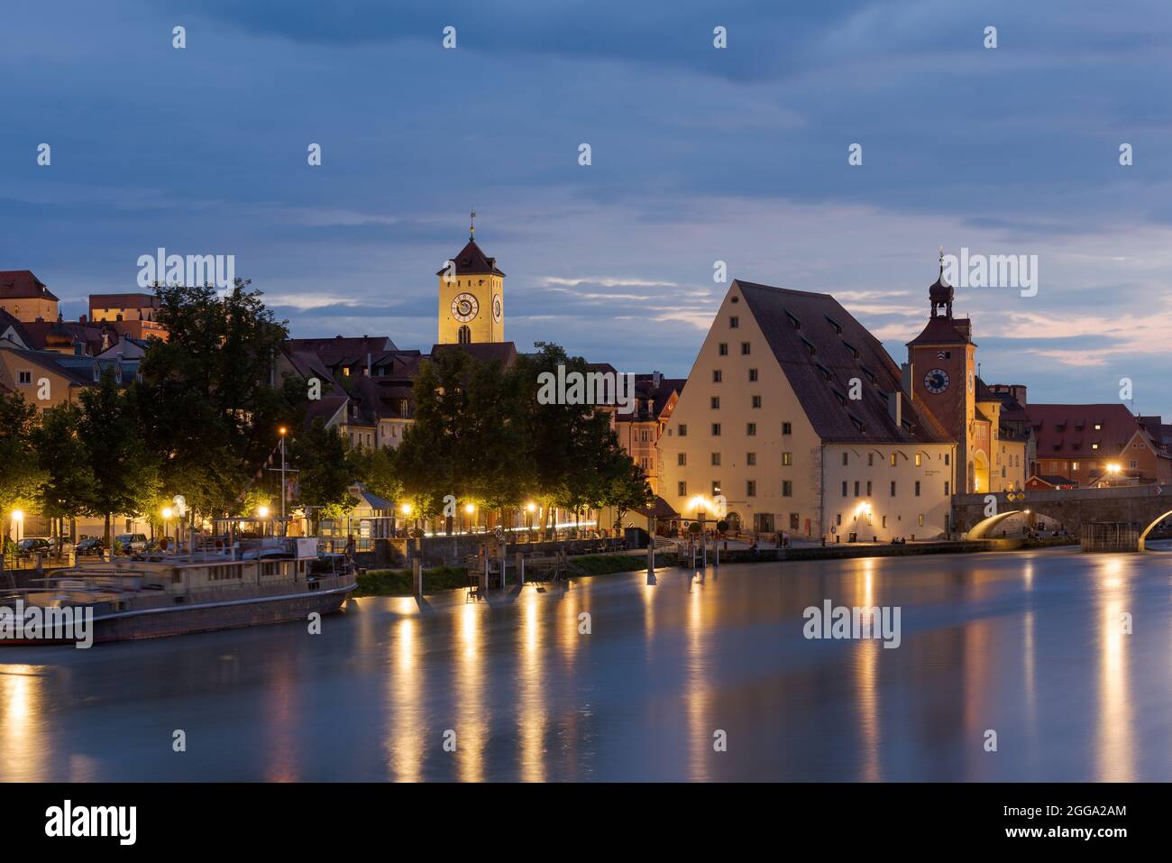 Torre del ayuntamiento de Regensburg y Salzstadel a orillas del río Danubio con puente de piedra por la noche Foto de stock