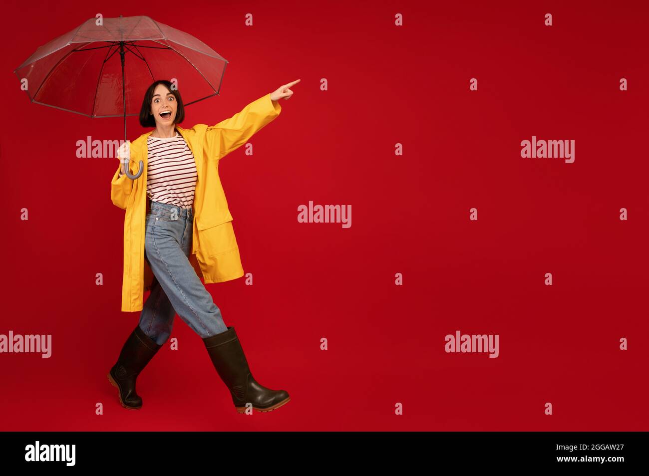 Chica joven con chubasquero amarillo con paraguas transparente en la  ciudad. Joven hermosa mujer con traje de lluvia y gafas mientras camina en  la calle. Con Fotografía de stock - Alamy