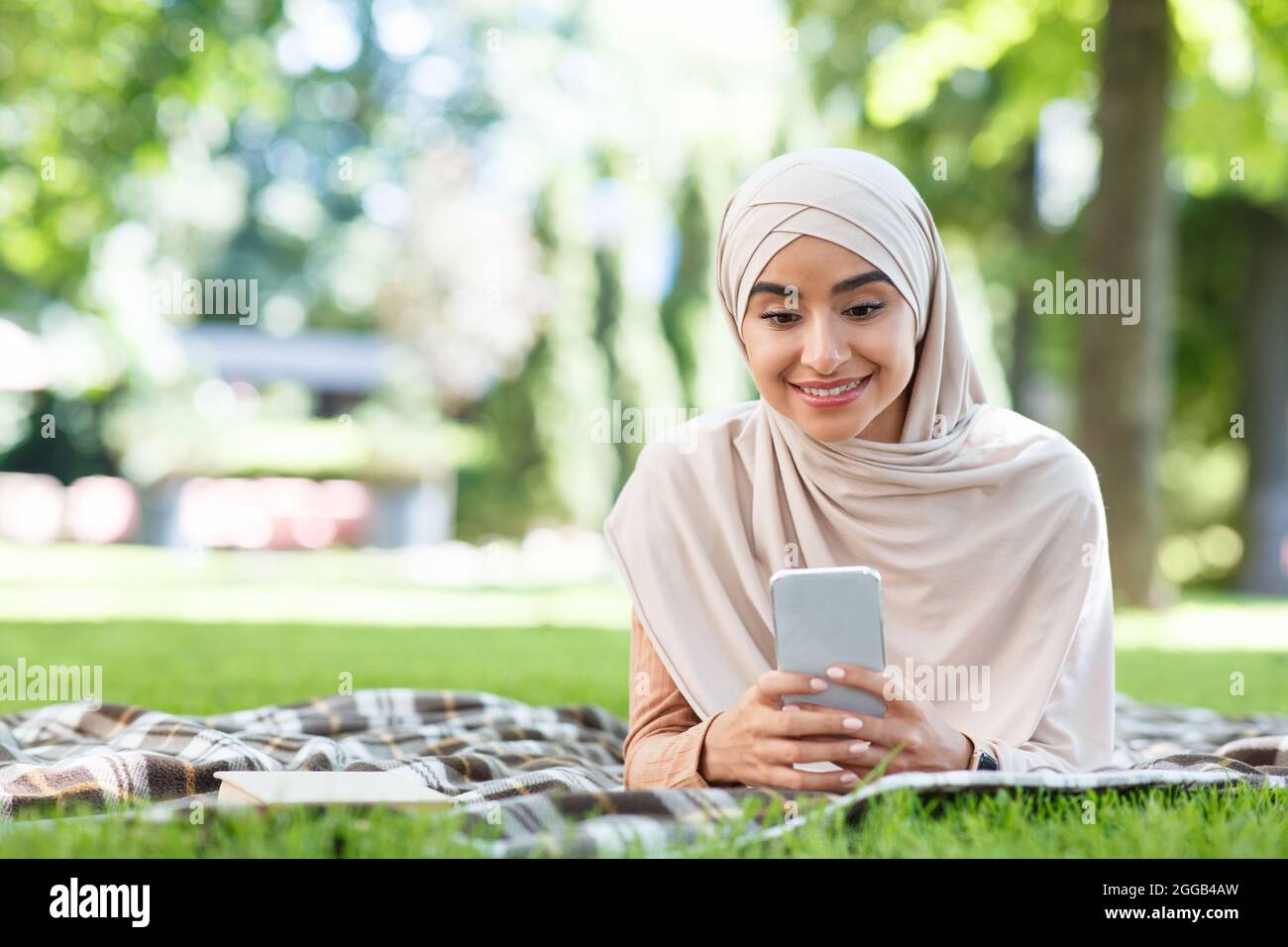 Feliz mujer descansar y relajarse en el descanso en el parque con las redes sociales, chat en línea y la nueva aplicación al aire libre después de covid-19 Foto de stock