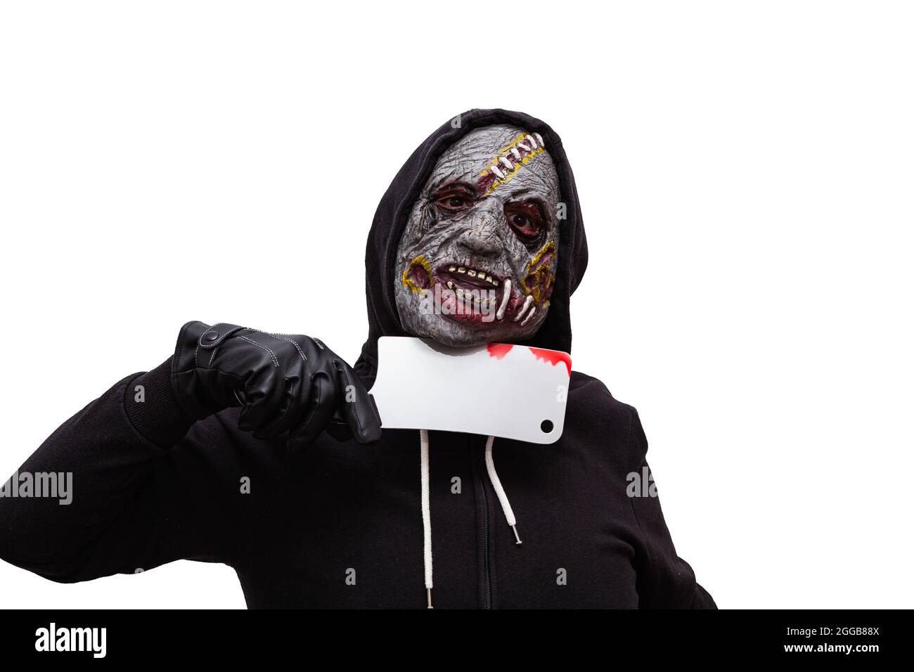 Un hombre vestido en una sudadera con capucha negra y disfrazado en una  máscara zombie tiene un cuchillo de carnicero sangriento presionado contra  su cuello. El fondo es blanco Fotografía de stock -