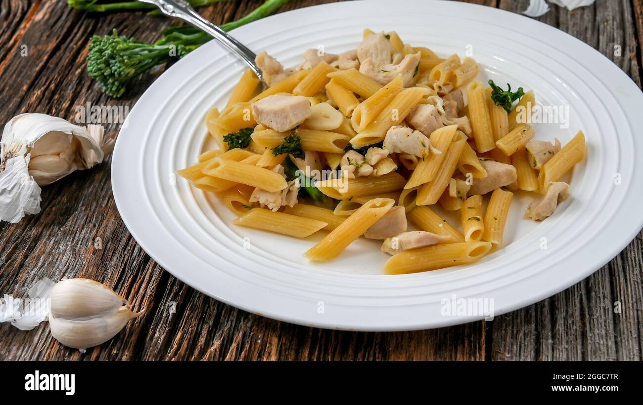 Pasta Penne con pollo, ajo y brocolii sobre mesa rústica de madera lista  para comer Fotografía de stock - Alamy