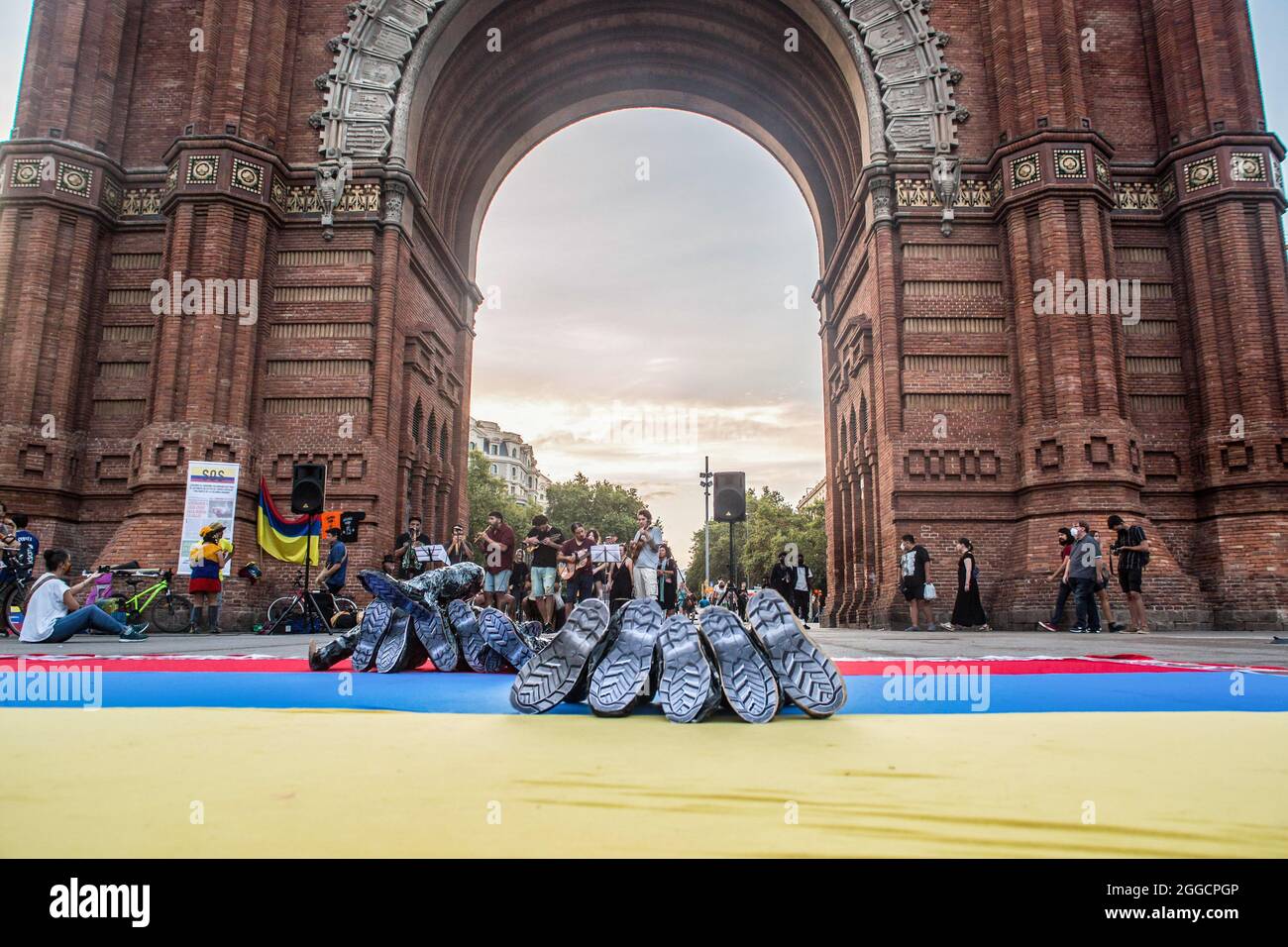 Las botas se ven en una bandera colombiana durante una manifestación frente  al Arc de Triomf en Barcelona. Cerca de 200 personas se han manifestado  frente al Arc de Triomf en Barcelona