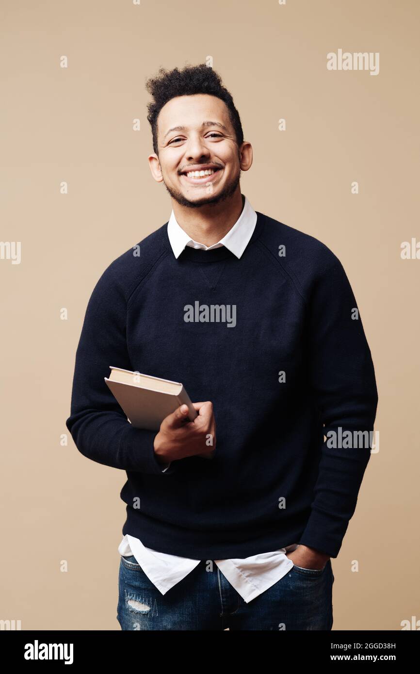 Hombre joven guapo con suéter, camisa blanca y gafas sobre fondo beige cara  sonriente mirando la cámara. Persona positiva, estilo profesor Fotografía  de stock - Alamy