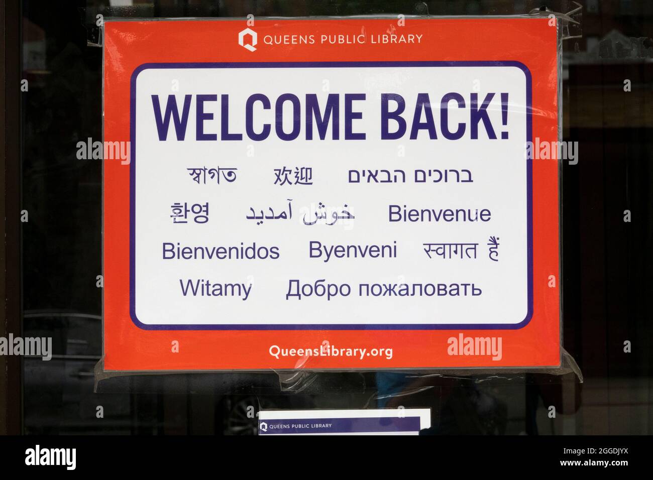 Un cartel en la puerta de la Biblioteca Lefferts en Richmond Hill que da la bienvenida a los visitantes en 11different idiomas. Foto de stock