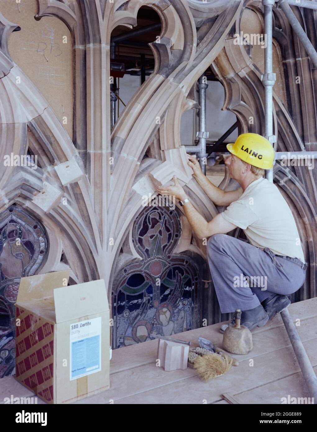 Una piedra Laing que trabaja en la restauración de la ventana este en la  Catedral de Carlisle, colocando un nuevo pedazo de piedra en la acería  usando masilla SBD Certita para enlazarlo
