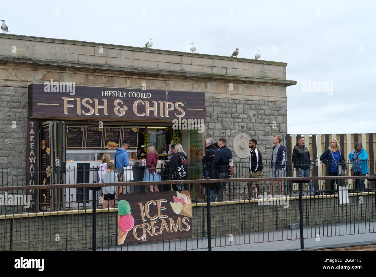 Los turistas hacen cola en una tienda de pescado y patatas fritas en Weston Super Mare, Reino Unido. Foto de stock