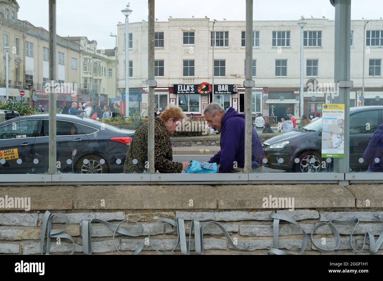 Una pareja comiendo pescado y patatas fritas en un refugio de autobuses en Weston Super Mare Foto de stock
