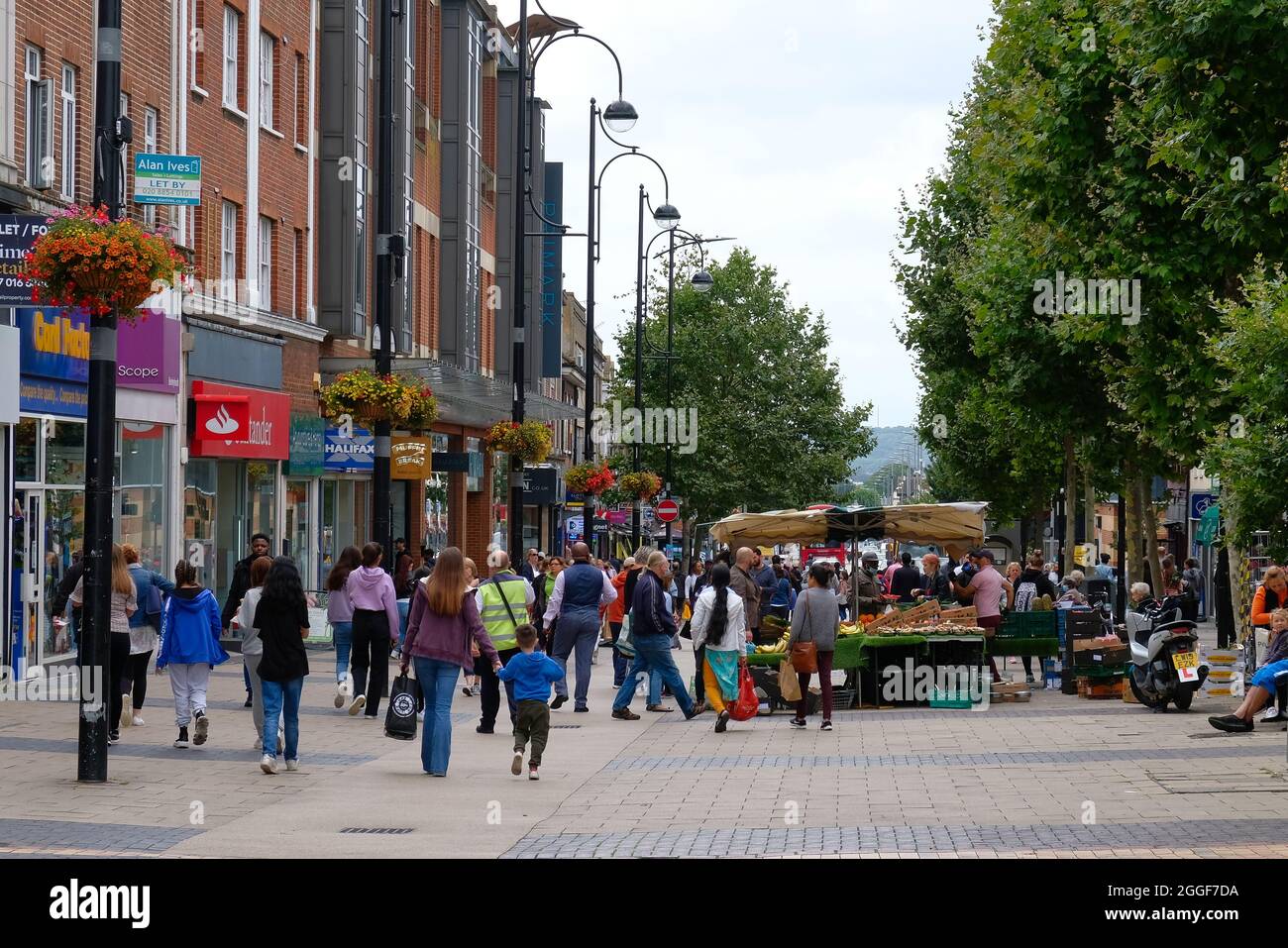 Bexleyheath Kent Inglaterra 08.31.21 personas mezclándose en una zona comercial peatonal al aire libre. Fachadas de tiendas y letreros. Puesto de mercado de verduras. Filas de t Foto de stock
