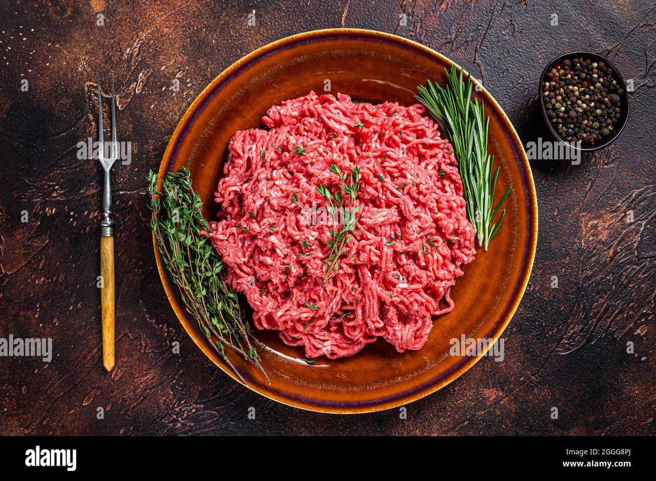 Carne cruda de carne picada y de cordero en un plato rústico con hierbas.  Fondo oscuro. Vista superior Fotografía de stock - Alamy
