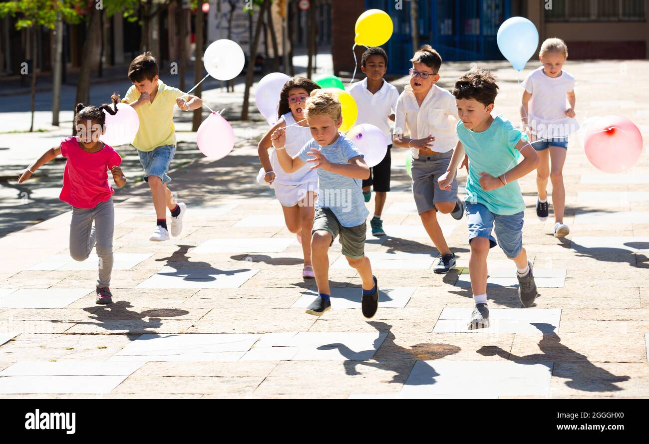 Niños con globos corriendo en la carrera y riendo en el día soleado  Fotografía de stock - Alamy