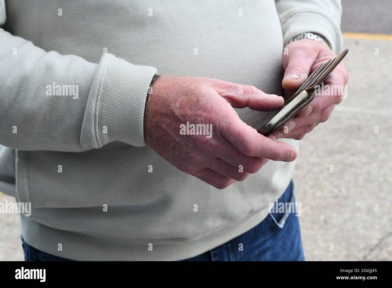Hombre buscando en la pantalla táctil del teléfono en un estuche de cuero marrón Foto de stock