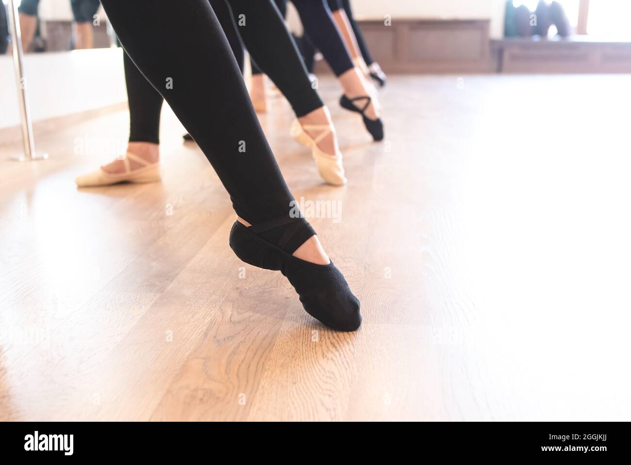 Sección baja de las elegantes piernas de los bailarines de ballet que están en fila en los dedos de los pies Foto de stock