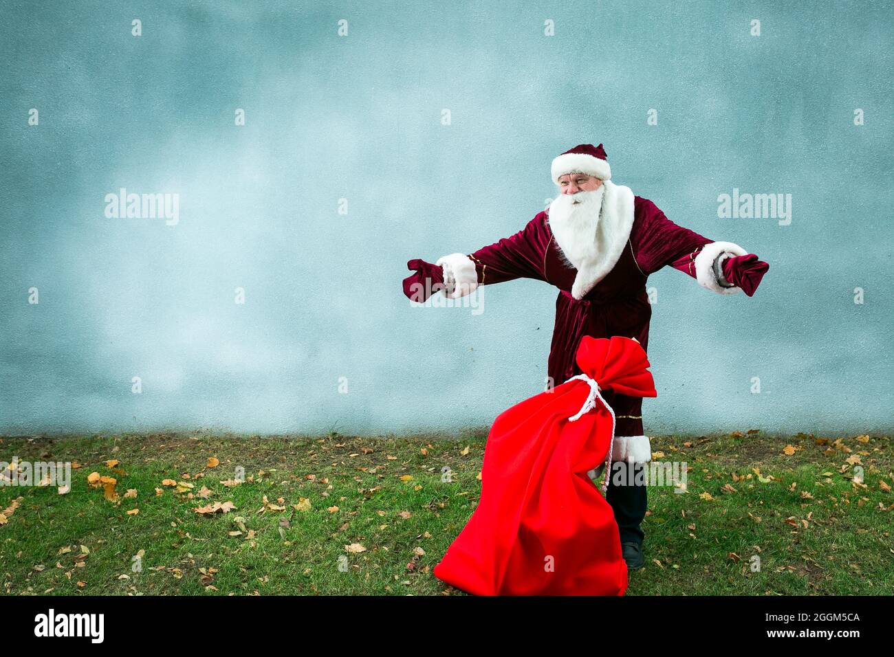 Papá Noel con una gran bolsa de regalos. Santa lanza sus manos y muestra lo  que una bolsa grande. Primer plano sobre fondo gris y hierba verde  Fotografía de stock - Alamy