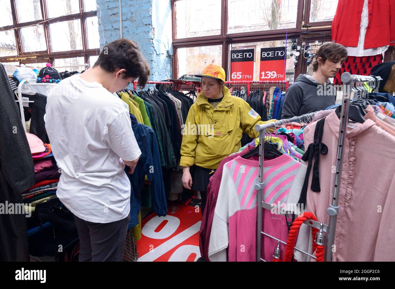 Rastro. Hombre joven escogiendo ropa de segunda mano en una tienda, mujer vendedora ayudándolo. de septiembre de 2019. Kiev, Ucrania Fotografía de stock - Alamy