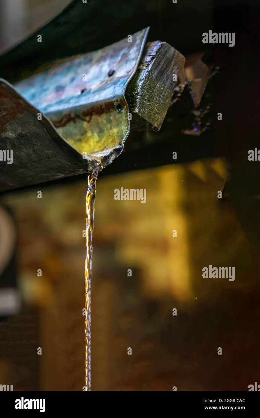 Lluvia, corriente de agua que cae del tubo de desagüe del techo cerca Foto de stock