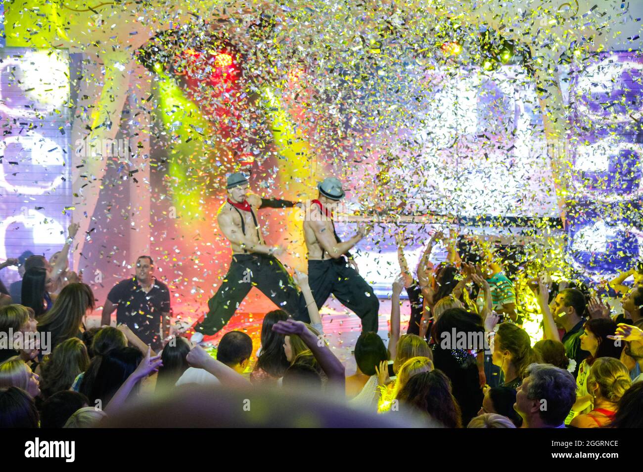 Odessa, Ucrania 28 de junio de 2013: Fiesta nocturna fiesta multitud de personas siluetas manos con confeti. Fiesta de discoteca. Luces coloridas durante dj par Foto de stock