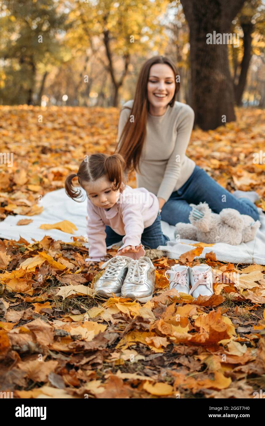 Vestir a niños para juegos al aire libre de otoño. Moda otoñal para bebés,  niños. Ropa y calzado de otoño para actividades al aire libre. Mamá y hija  pequeña Fotografía de stock -