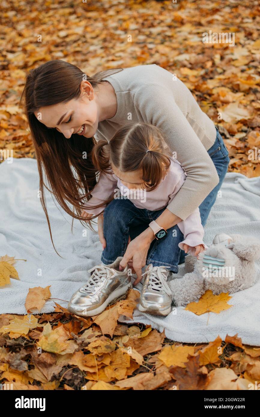 Vestir a niños para juegos al aire libre de otoño. Moda otoñal para bebés,  niños. Ropa y calzado de otoño para actividades al aire libre. Mamá y hija  pequeña Fotografía de stock -