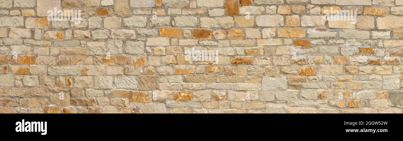 Antigua pared panorámica de piedra gruesa en beige, ocre y marrón Foto de stock
