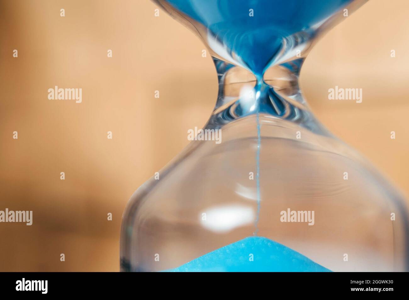 Arena que corre a través de los bulbos de un reloj de arena que mide el tiempo que pasa en una cuenta atrás a una fecha límite, sobre un fondo oscuro con espacio de copia. Foto de stock